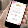 Convite com floral rosa para 15 anos exibido em celular, com moldura dourada, flores delicadas e coroa decorativa.