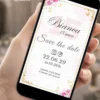 Save the Date digital na cor rosa para aniversário de 15 anos, com flores cor-de-rosa, detalhes dourados e moldura delicada.
